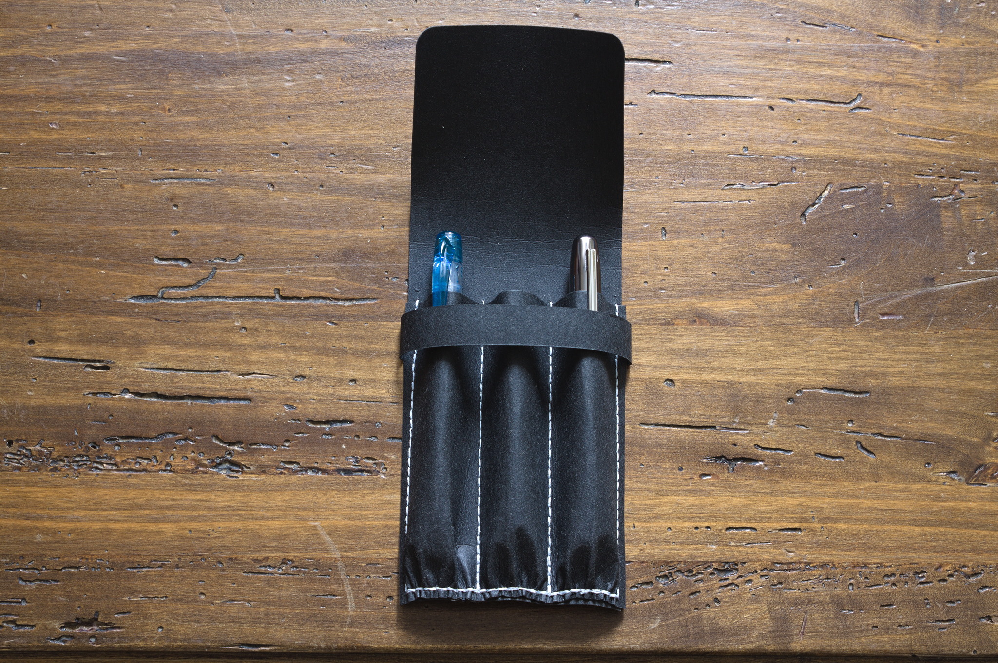 The open pen case, showing two pens, a blue Preppy and a
gunmetal Plaisir cosily nested in the two outer slots, while the
middle slot is ominously empty.