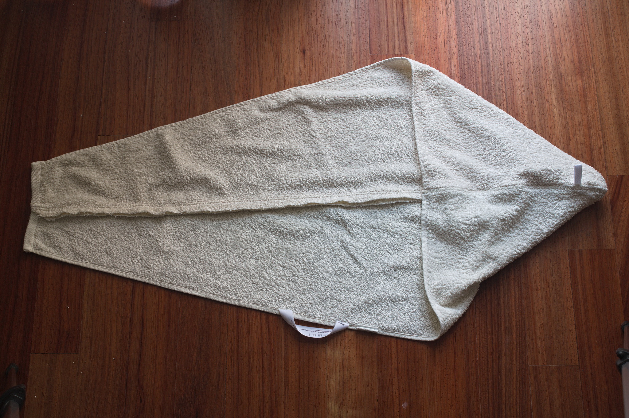 A towel, with its original care label, that has been cut in a
trapezoid shape and reassembled into a hood shape with a long
triangular tail. The machine sewn finishing is still neat and
pristine.