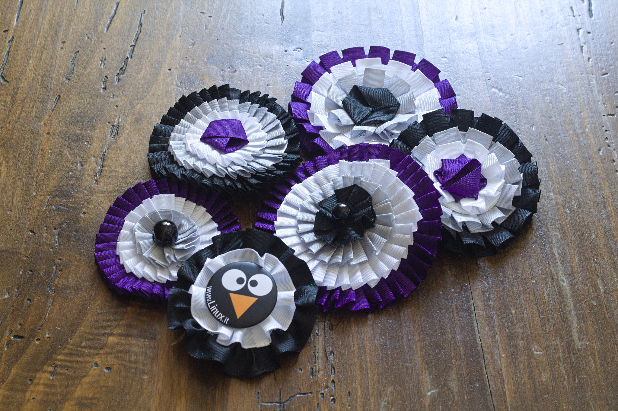 six cockades in black, grey, white, purple, in different sizes
and with different centrepieces. One is only black and white and
has a penguin pin in the middle.