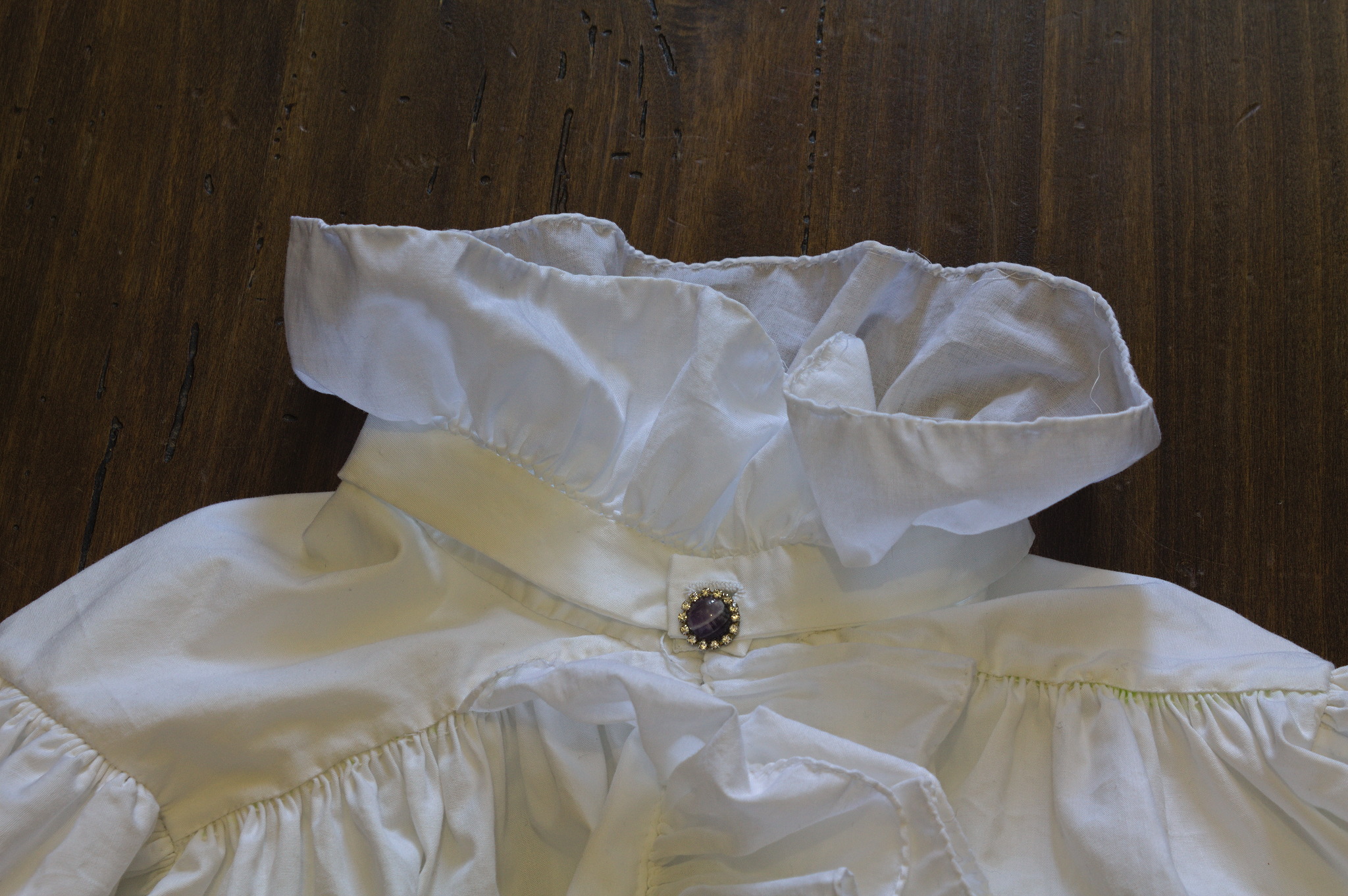 Same close up, but now the collar has been closed with a
clip-on earring with an amethyst and some small fake clear stones,
and it looks as if the skirt had a ruffle collar and a jewel
button (or a pin).