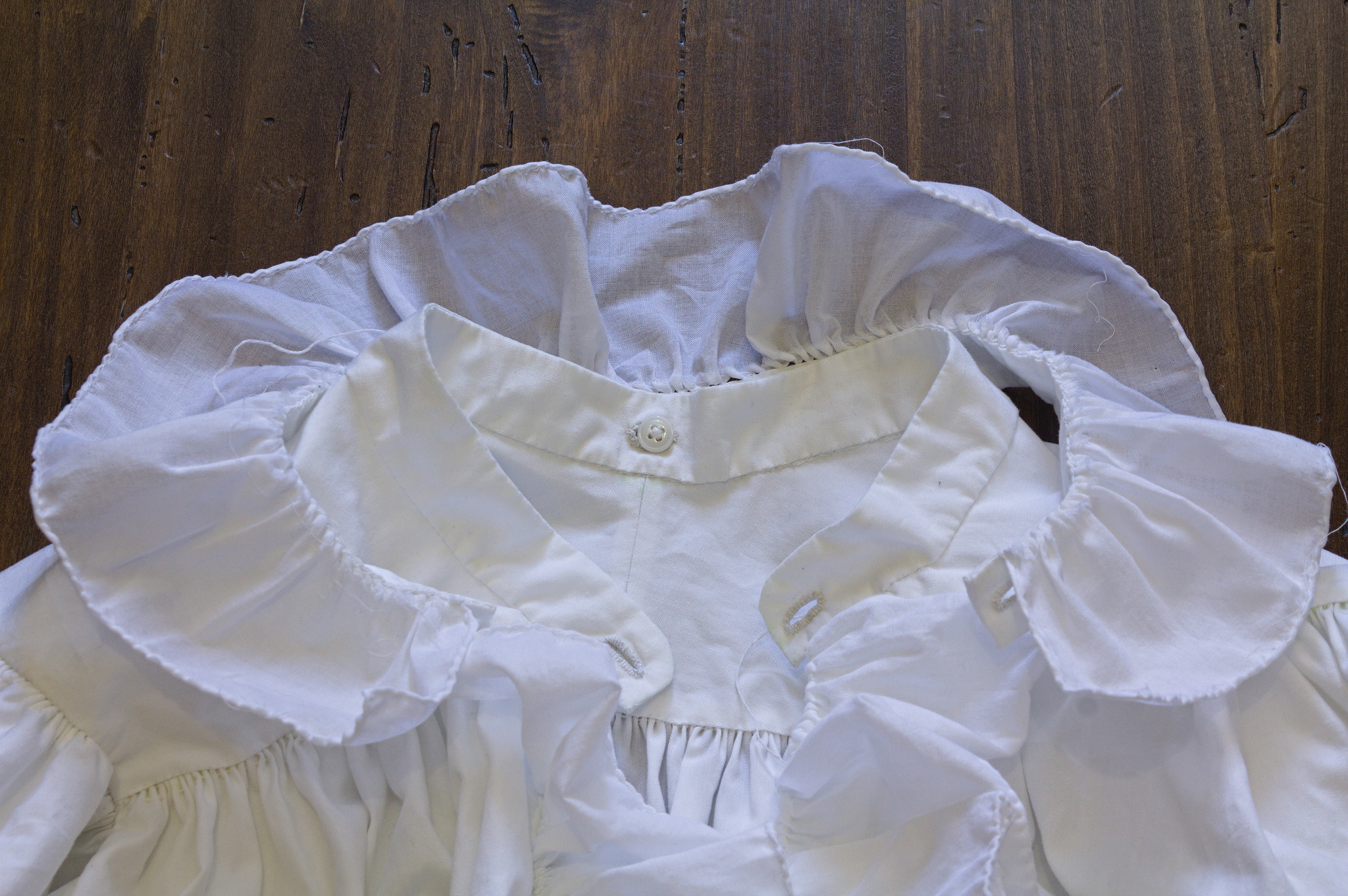 Close up of the collar on a table: at the center back of the
shirt collar there is a buttonhole, and a double button is used to
keep the detached collar in place, while at the front both the
shirt collar and the detached collar have buttonholes.