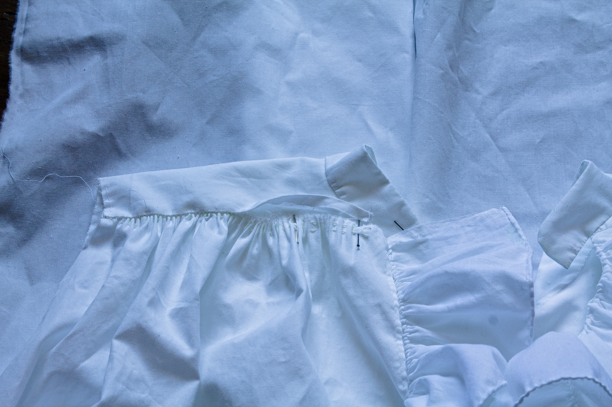 The front of a shirt: the body was gathered into a yoke, but it
has been unpicked and pulled out to extend a bit past the end of
it, into where the collar will be sewn.