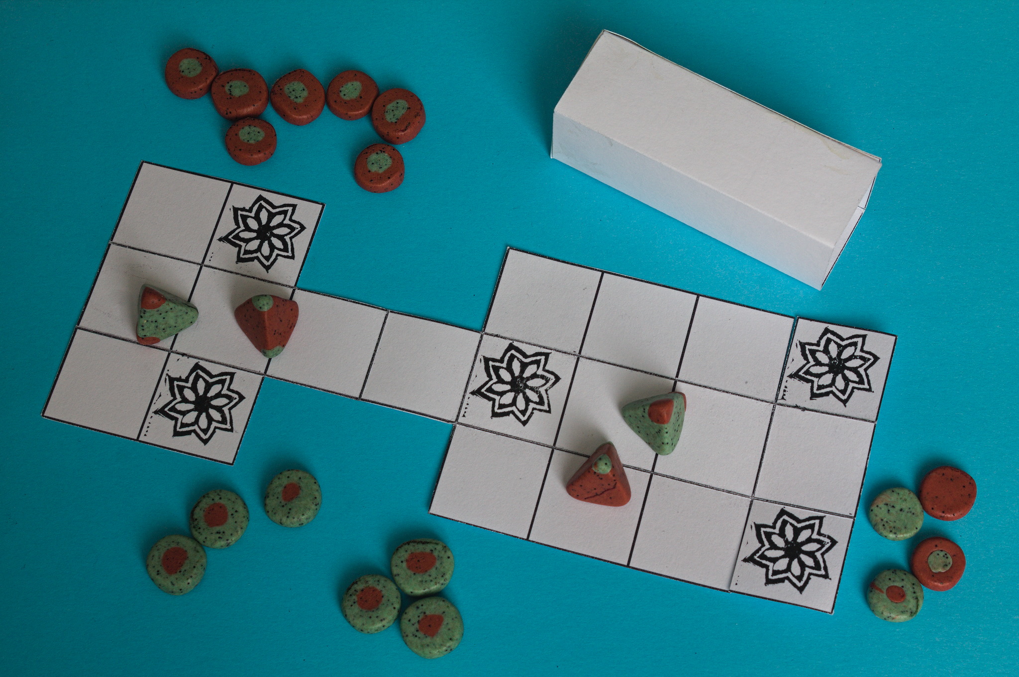 A set of red and green tokens, like the ones above, plus
tetrahedron dice and four more coins with a dot of a
different colour just on one side. Everything is on top of
a board that folds up.