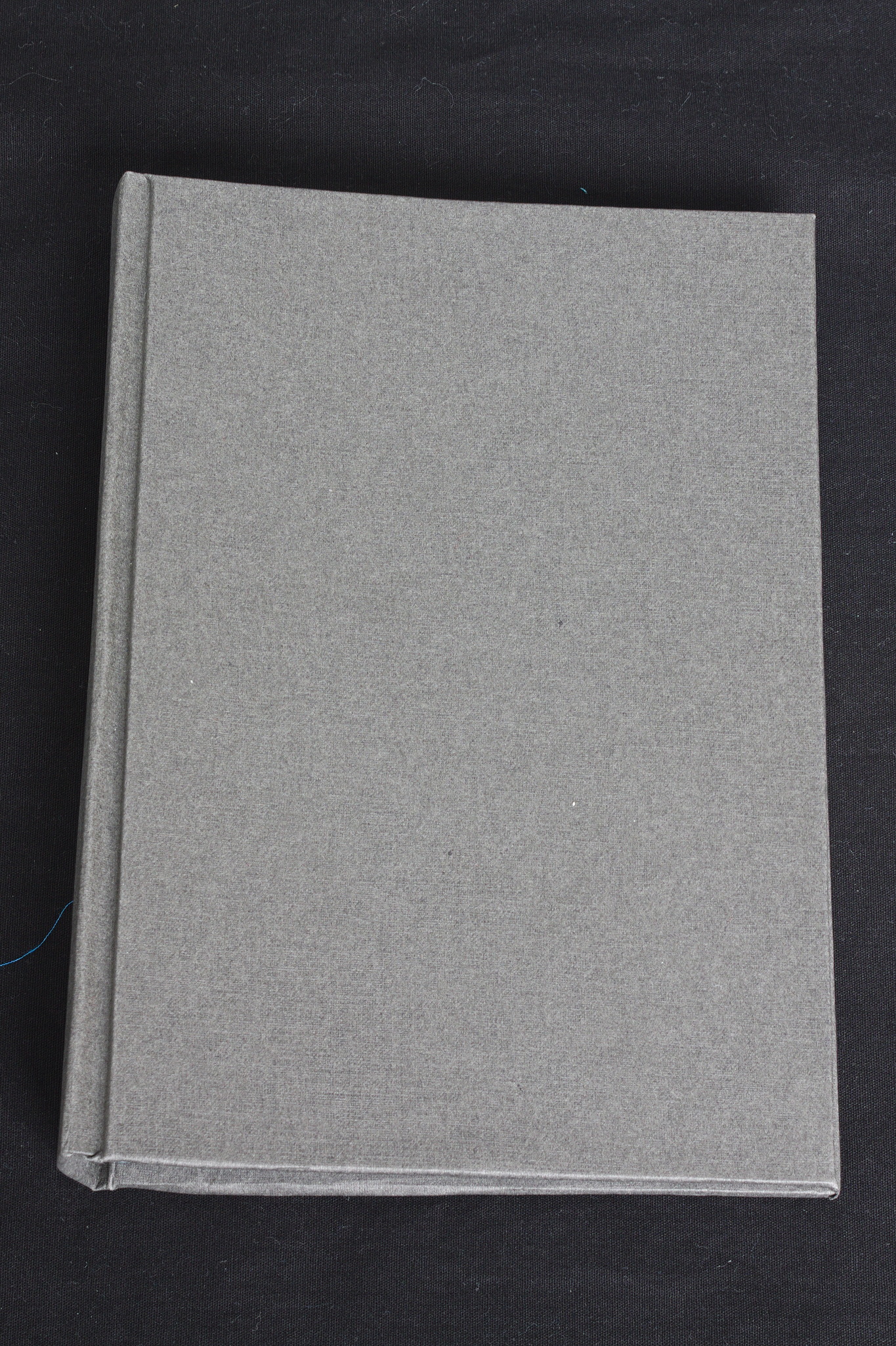 A closed hardcover book in uniform dark grey.