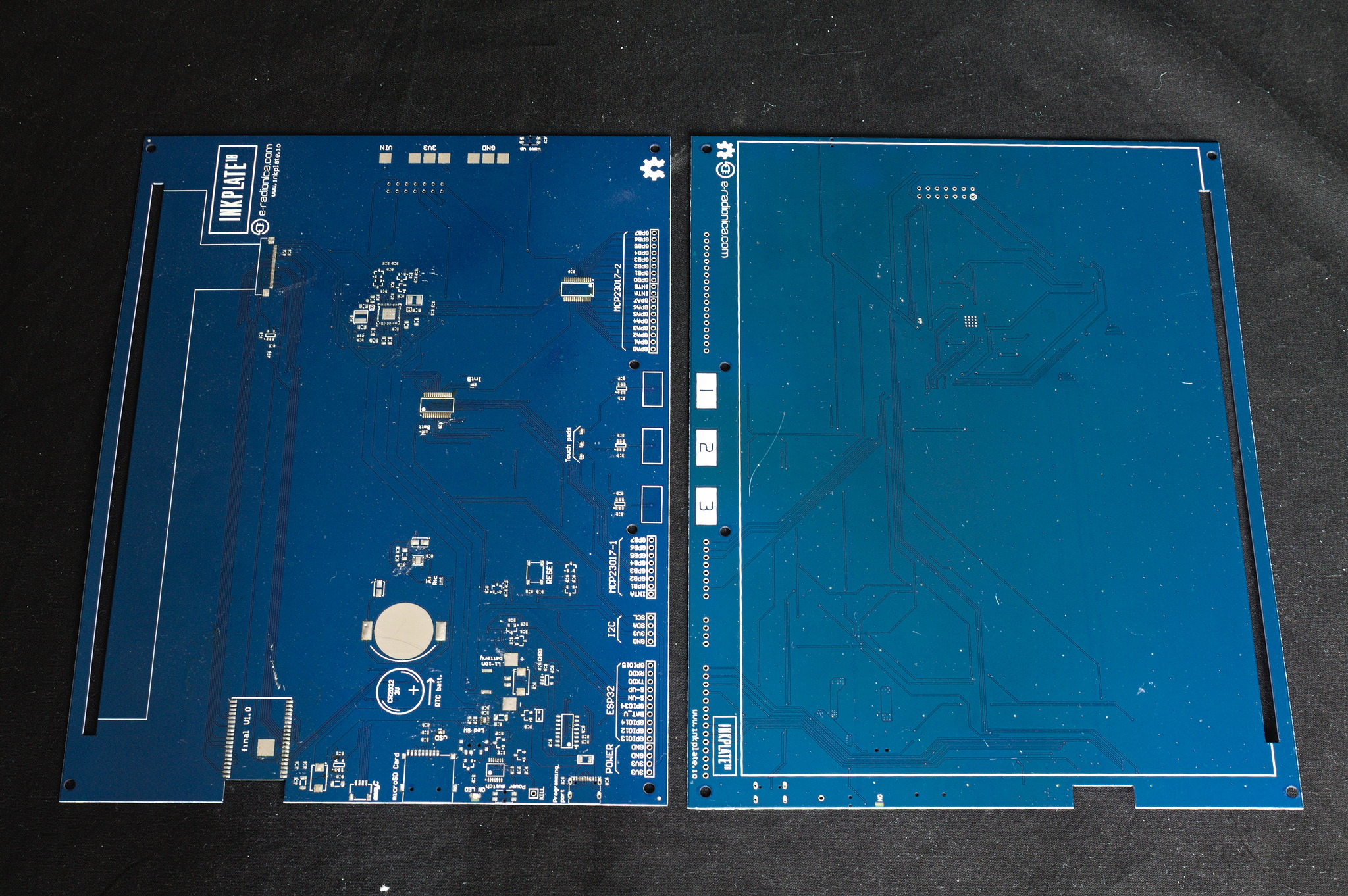 Two PCBs for the Inkplate 10 from eradionica, unpopulated.
They are rectangles with a long slit close to one long side, a
few holes and a notch at the bottom.