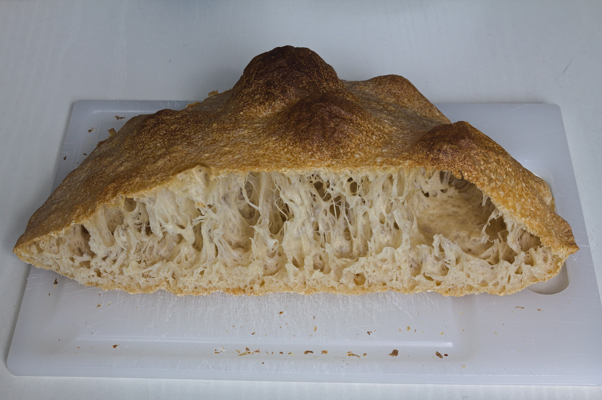 the loaf cut in half, to show thin stripes of crumb from the high hydration.