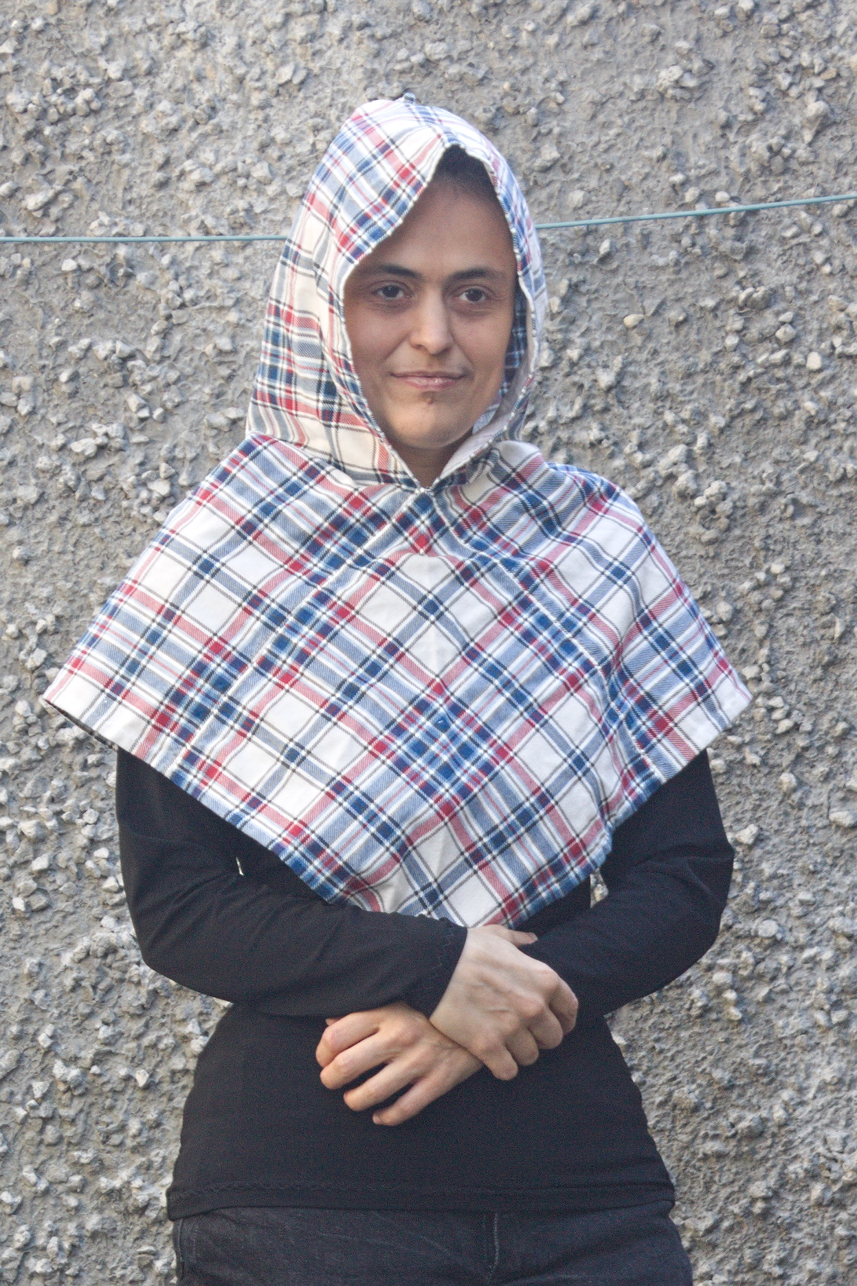 A woman wearing a hood in the same shape, but made in
tartan-print flannel.

It looks slightly smaller than the linen one.