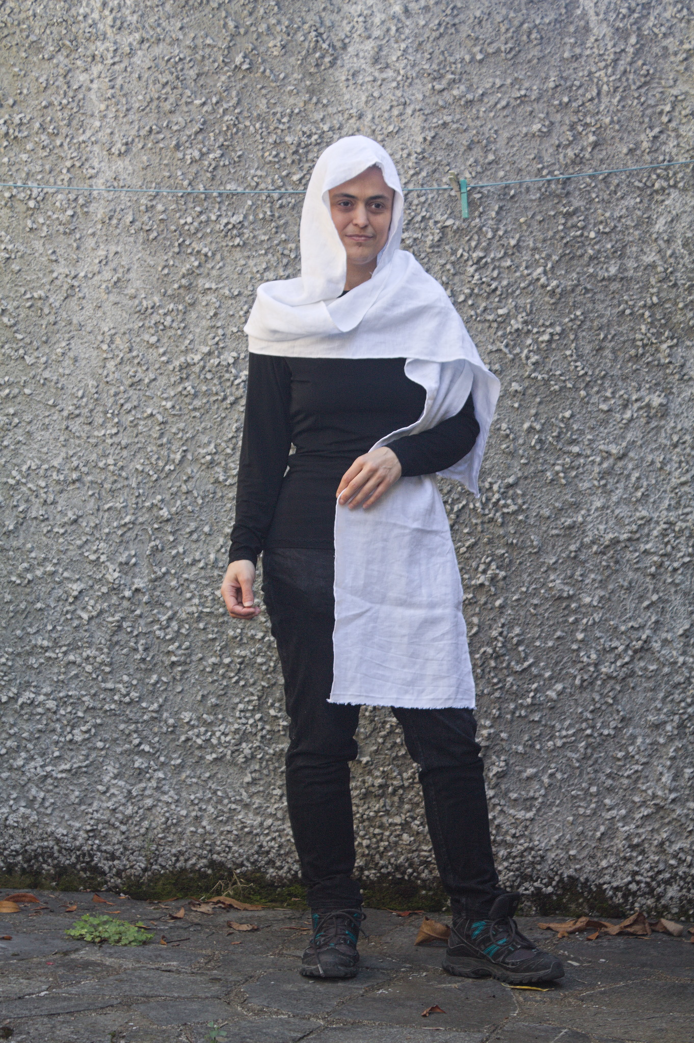 A woman wearing some sort of white veil that covers the head
and has two scarf-like appendages, one wrapped around the
shoulders and falling on the back, and one falling on the front
side, kept in place with one arm.