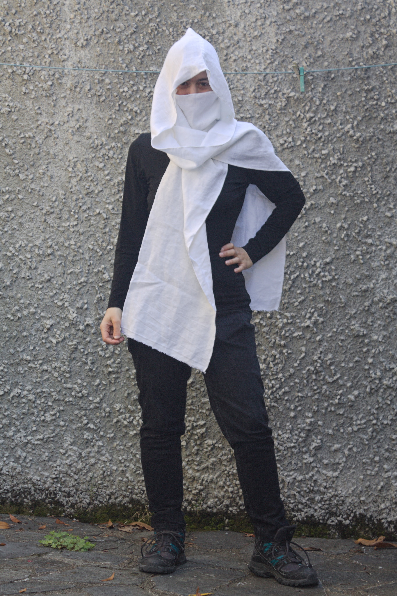 A woman wearing what looks like a deep hood over some sort of
fabric face mask, showing only the eyes, in a way that resembles
characters in a video game.

There are again two scarf-like edges that fall on the front and
back.