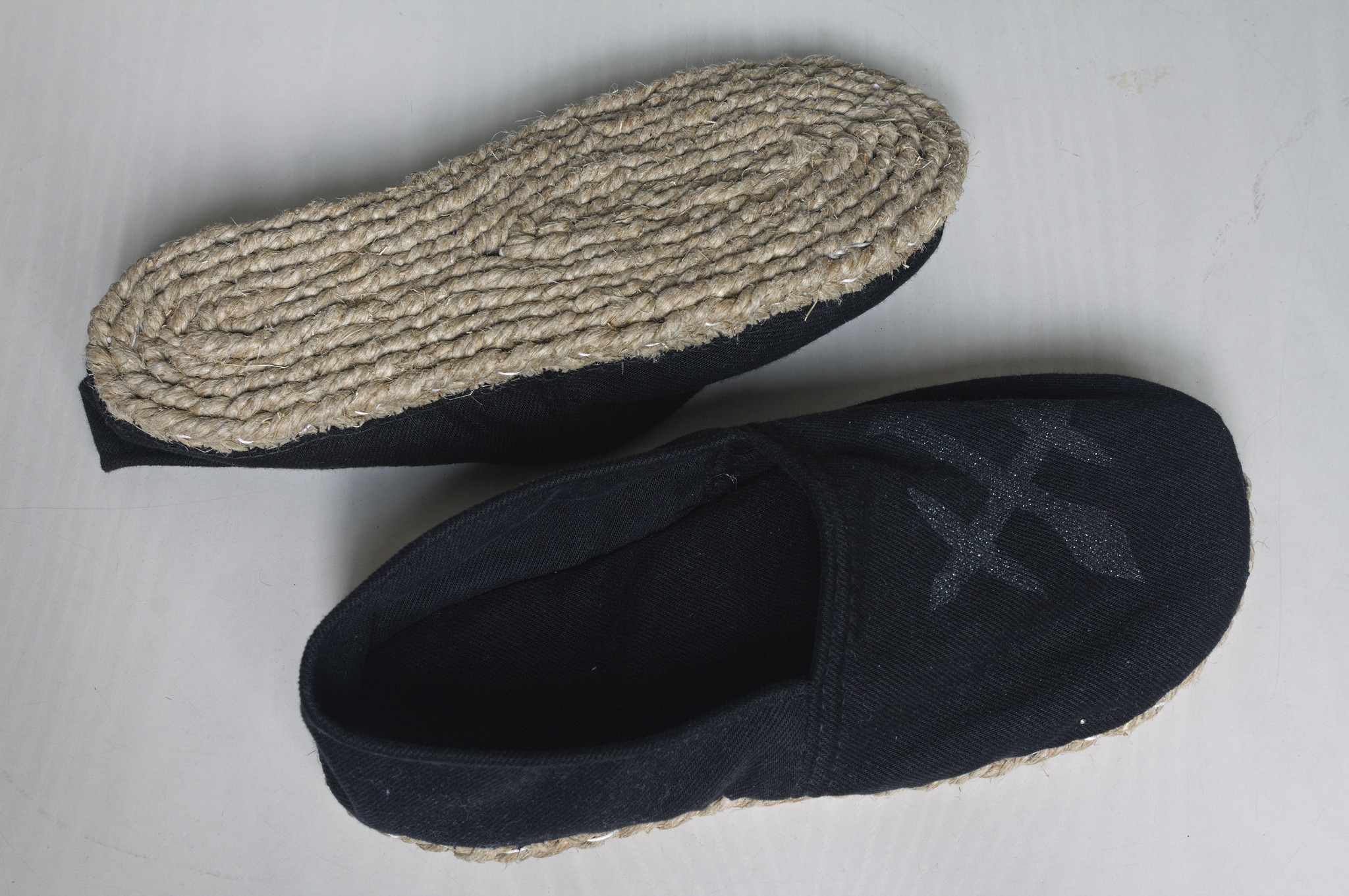 The same slippers, one of them is turned upside down to show
the sole made from a twine braid, sewn in a spiral until it is the
shape of a sole.