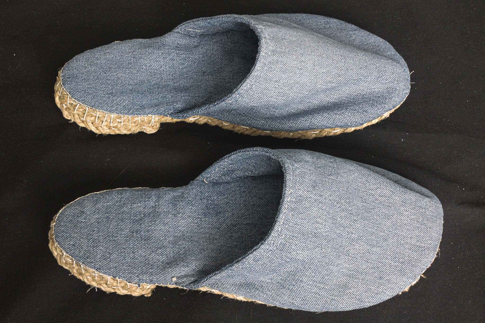 A pair of open-heeled slippers in faded blue jeans.