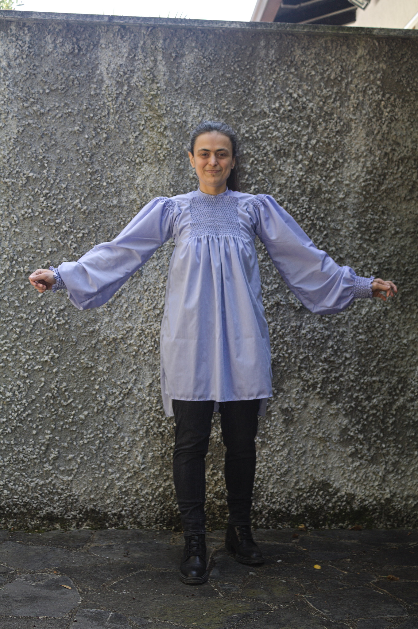 The same woman with arms wide to show the big sleeves and the
shirt unbelted to show that it is pretty wide also from the front,
below the yoke and the honeycombing.
The back can be seen as about 10 cm longer than the front.
