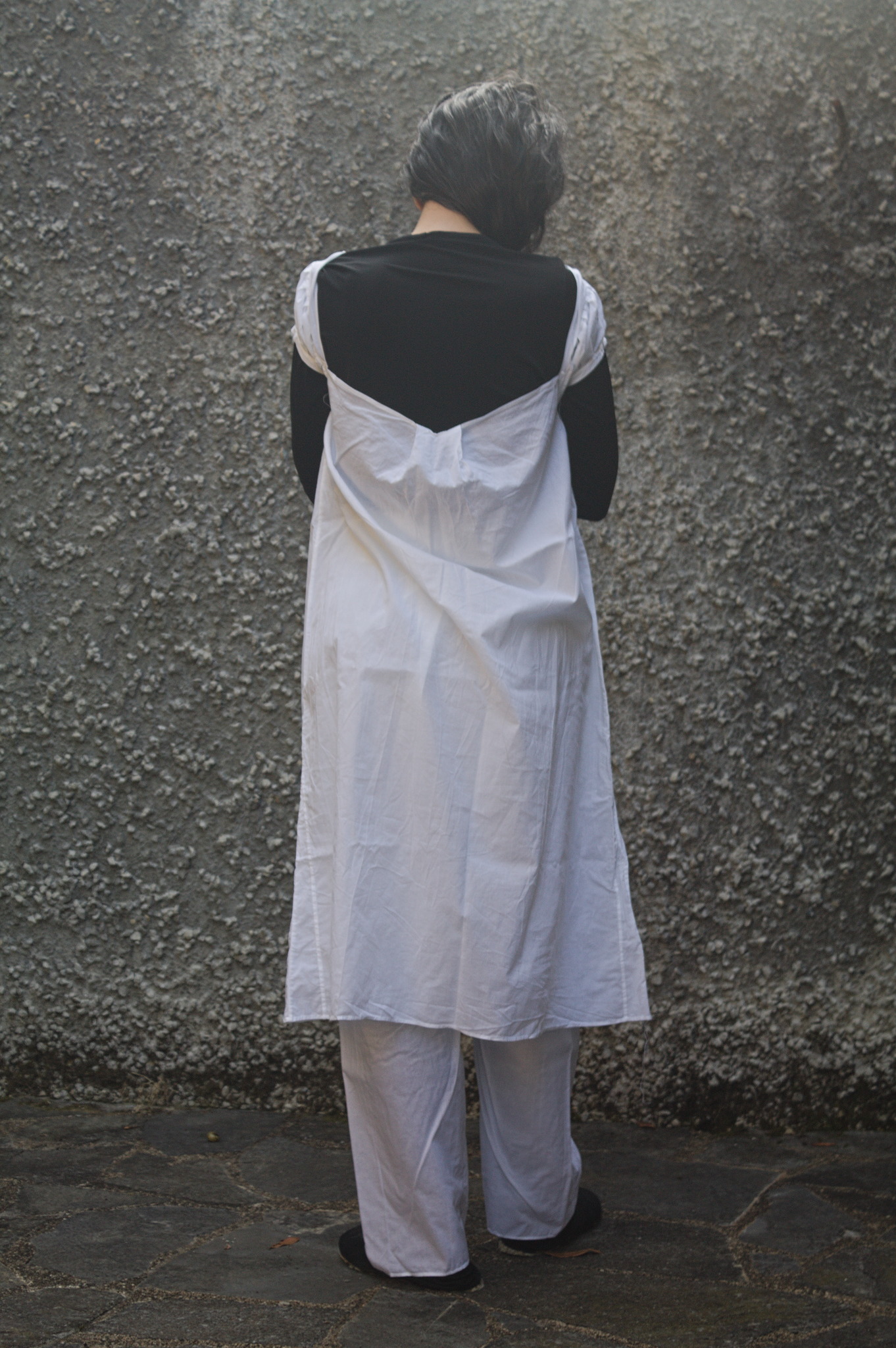 The same woman as in the opening image from the back, the shift
droops significantly in the center back, and the shoulder straps
have fallen down on the top of the arms.