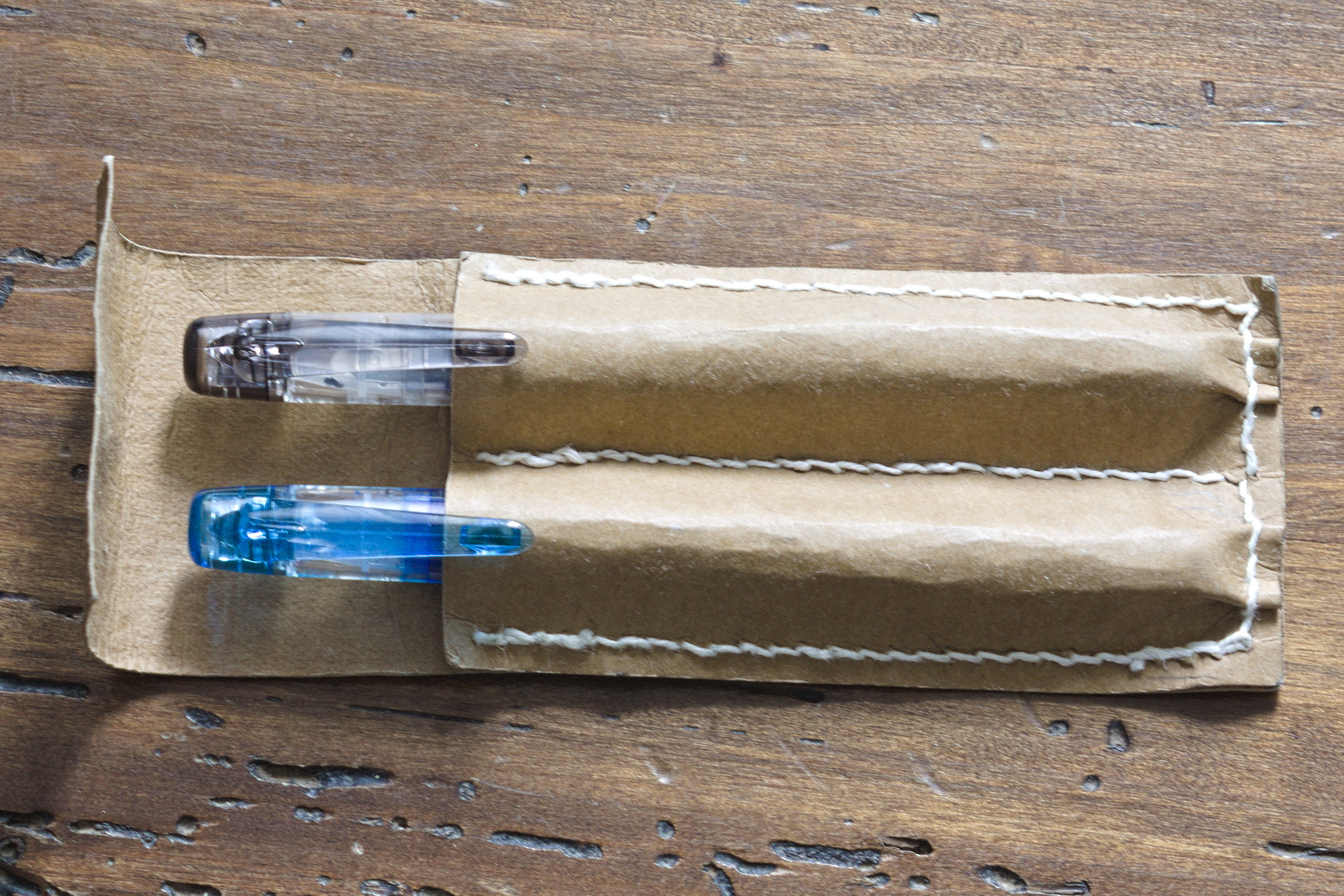 A two slot pen case in the same material as above, but brown: the flap is too short to cover the pens, and there isn't a band to keep it closed.