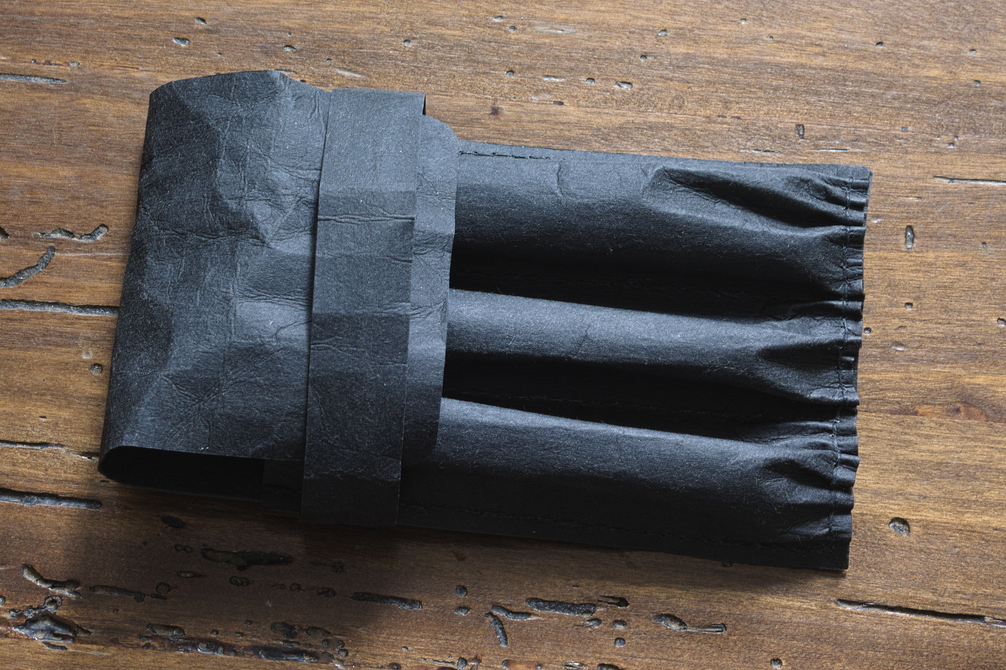 A case like the one above, except that the stitches are in black, and not as regular. This one has also been scrunched up a bit for a different look, and now the band is a bit too wide.