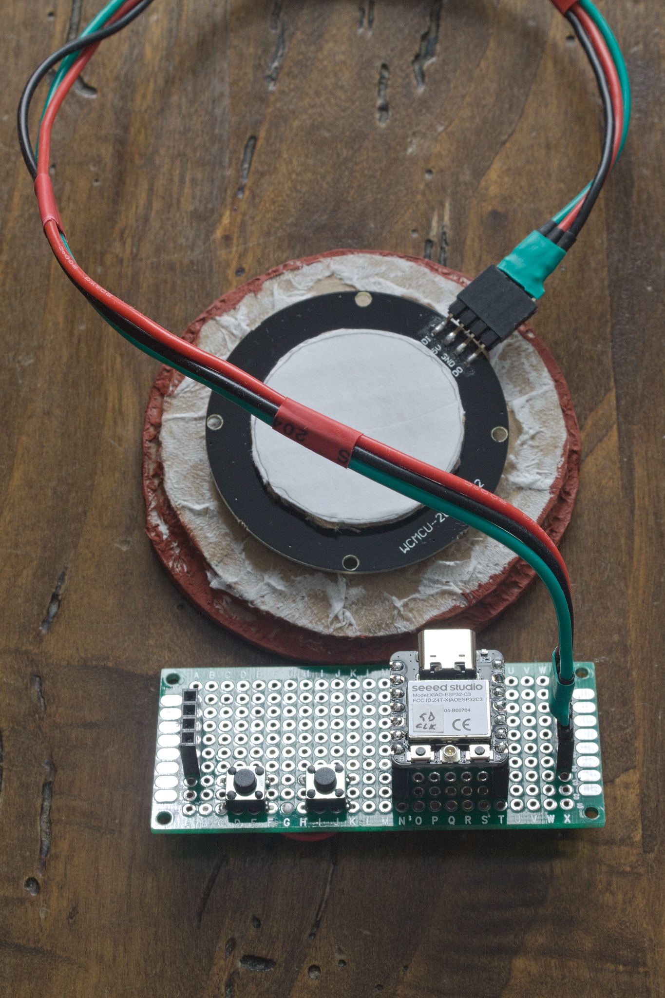 a LED ring mounted on the back of structure made out of circles
of cardboard in different sizes, glued together; it's connected
with wires kept together with heat shrink to a perfboard with a
couple of connectors, two buttons and a small microcontroller
board (details on which are in the next paragraph).