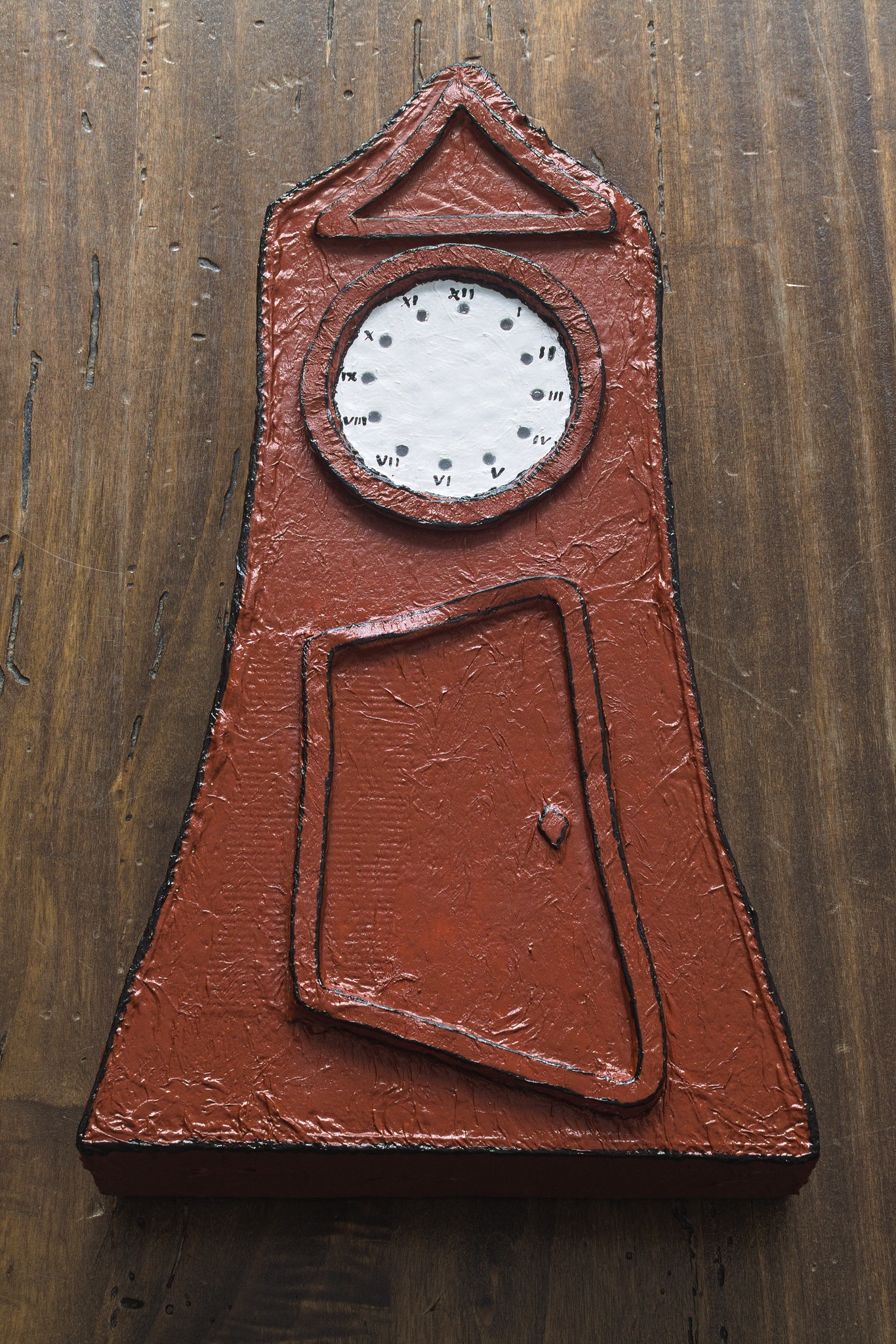 a paper maché object in the shape of a cartoony grandfather
clock with a somewhat irregular shape, painted reddish brown
except for the white face.